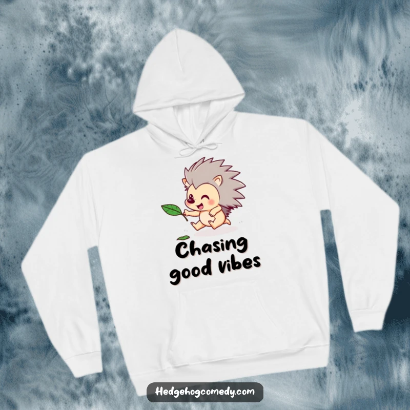 Funny hoodie featuring an energetic hedgehog character chasing a falling autumn leaf. Cozy and humorous seasonal design.